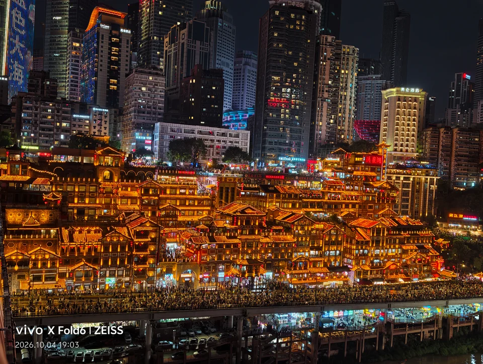 夜色中亮起金色灯光的层叠建筑与背后的高楼