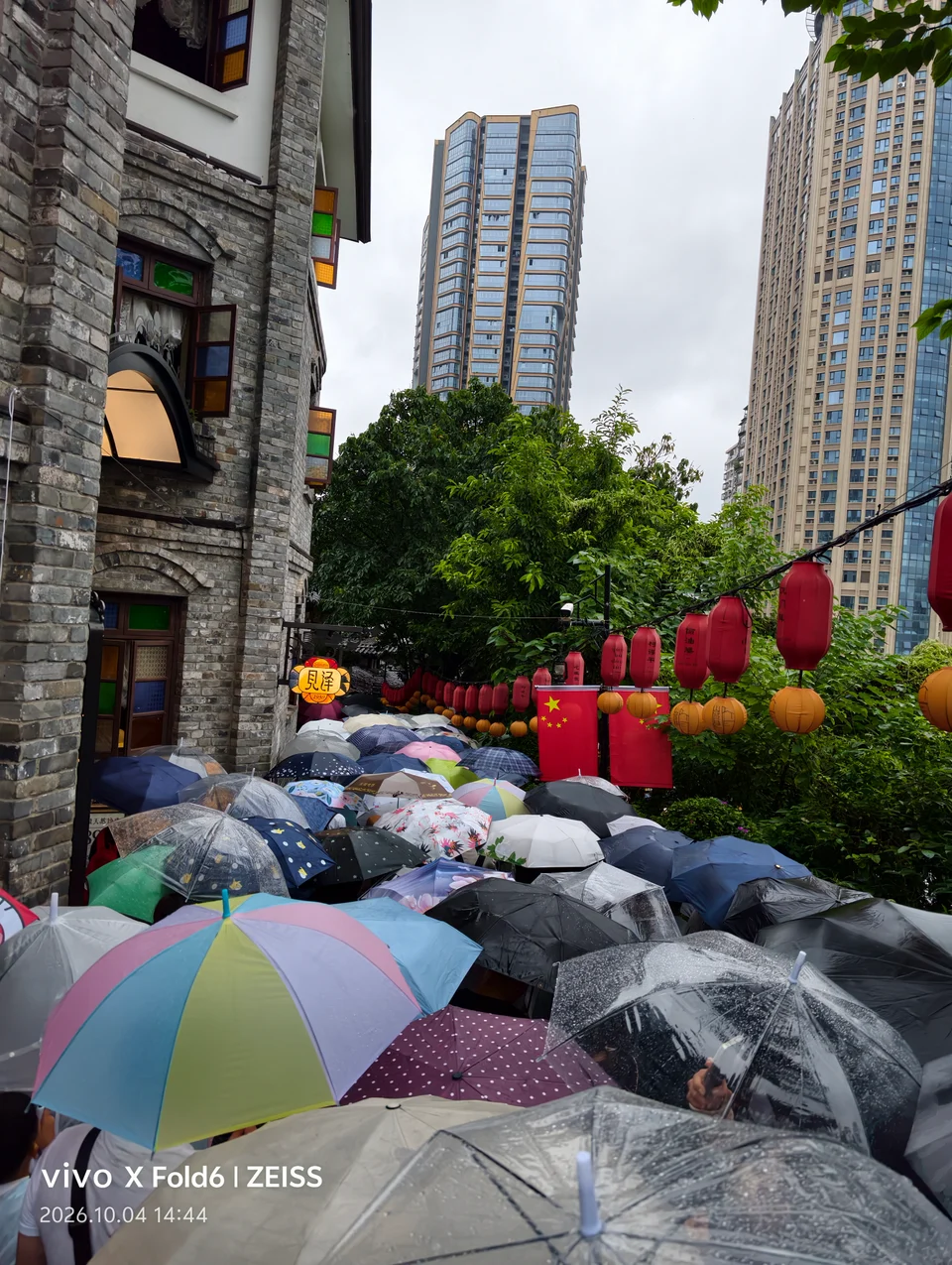 红灯笼下挤满雨伞的街巷，远处是高楼